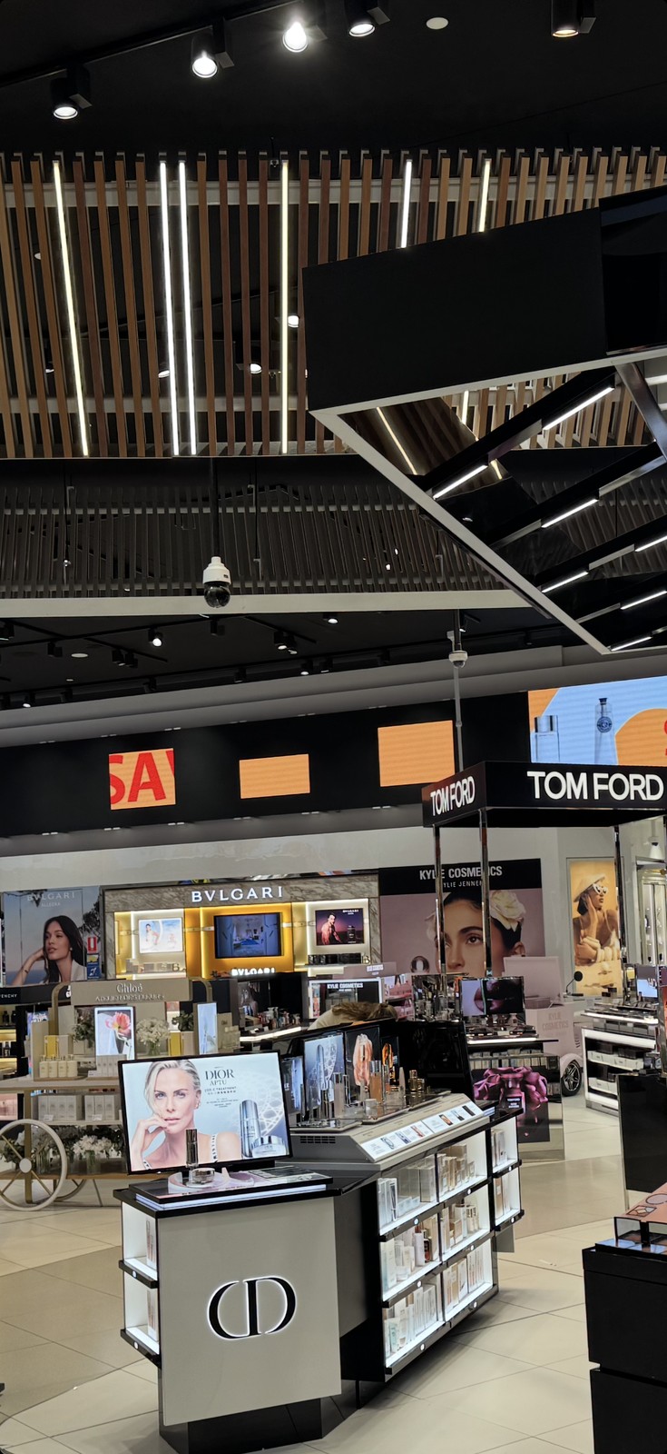 Melbourne Airport duty-free — three blank orange LED cabinets (dropped content) visible across the live ribbon